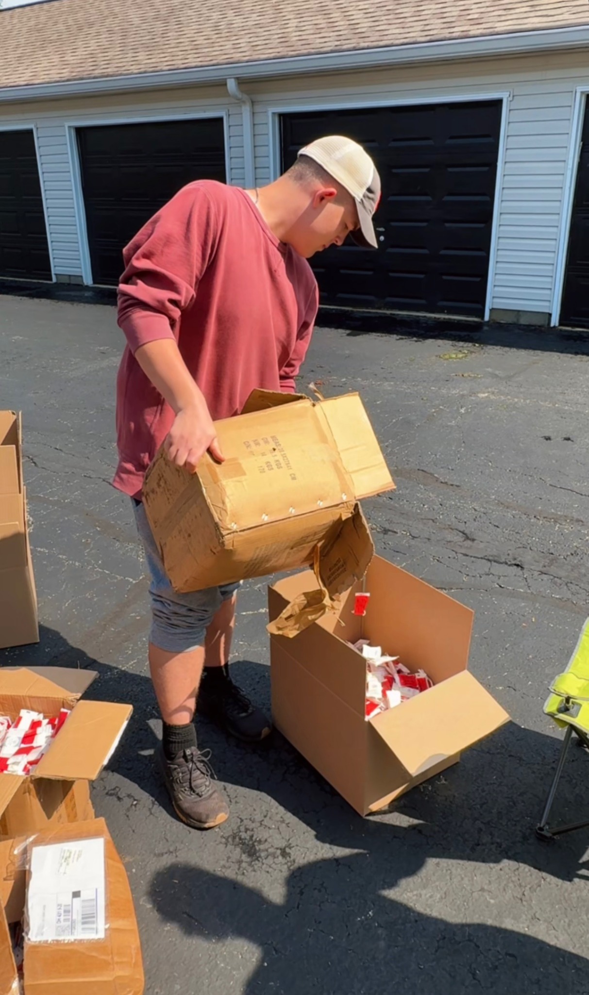 A volunteer transferring wrapped supplies between cardboard boxes outside the SOAP Project service site.