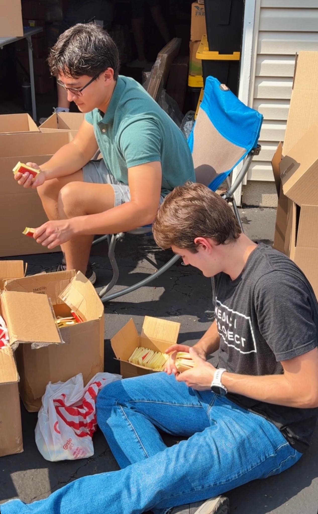 Two volunteers sorting individually wrapped soap into cardboard boxes at the SOAP Project service day.